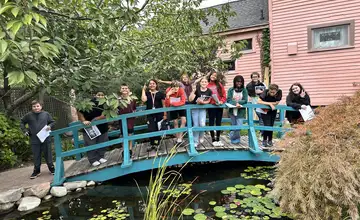 Students waving on a blue garden bridge