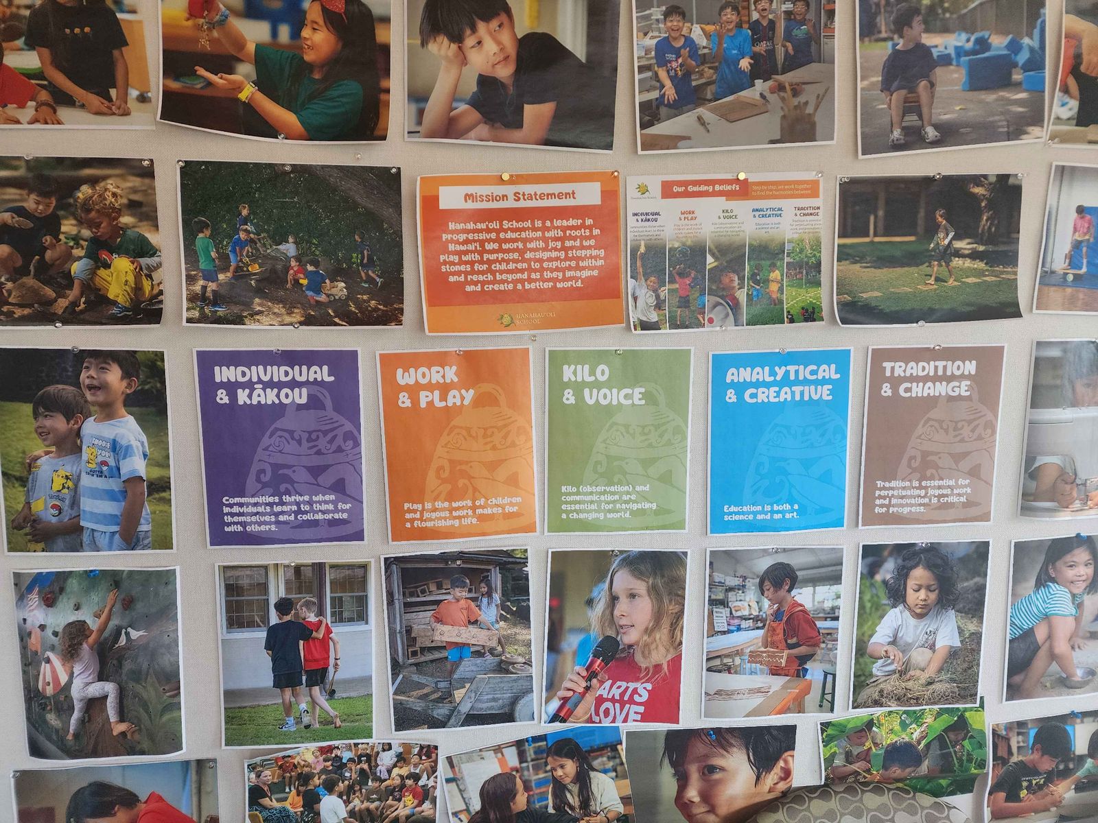 A wall of student photos surrounding the school's mission statement and five colored posters of its guiding beliefs: Individual & Kākou, Work & Play, Kilo & Voice, Analytical & Creative, and Tradition & Change.