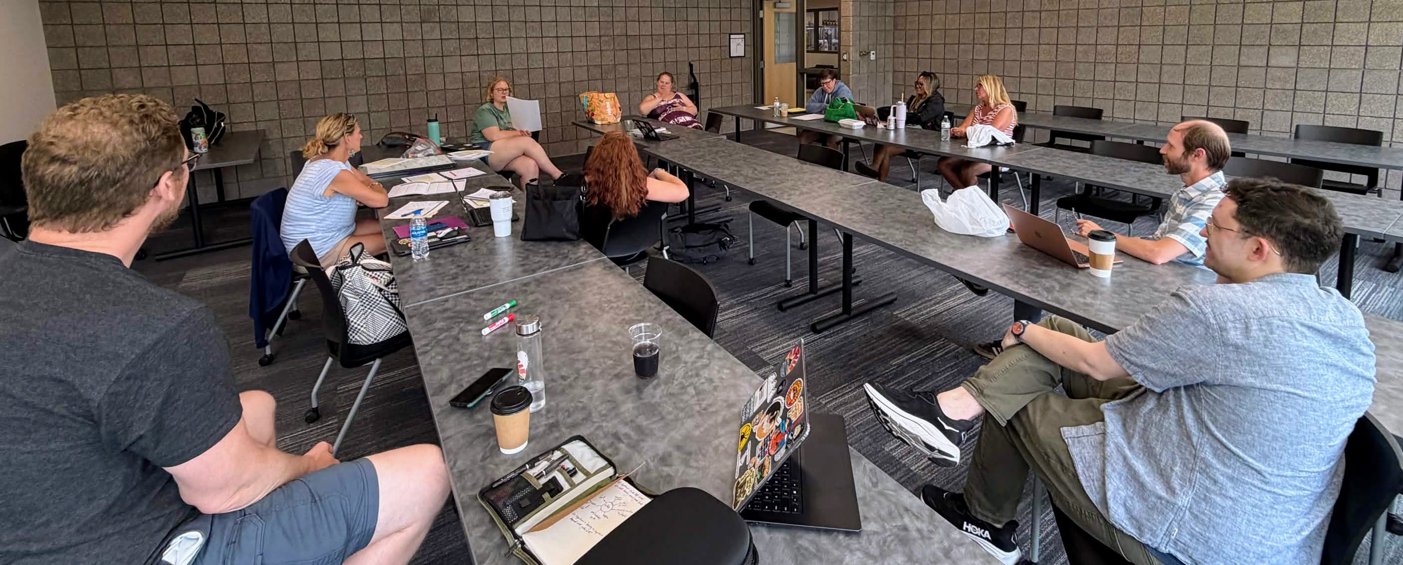 Teachers and HRP staff seated around a long table in a Muskegon classroom during a summer TCLC planning session.